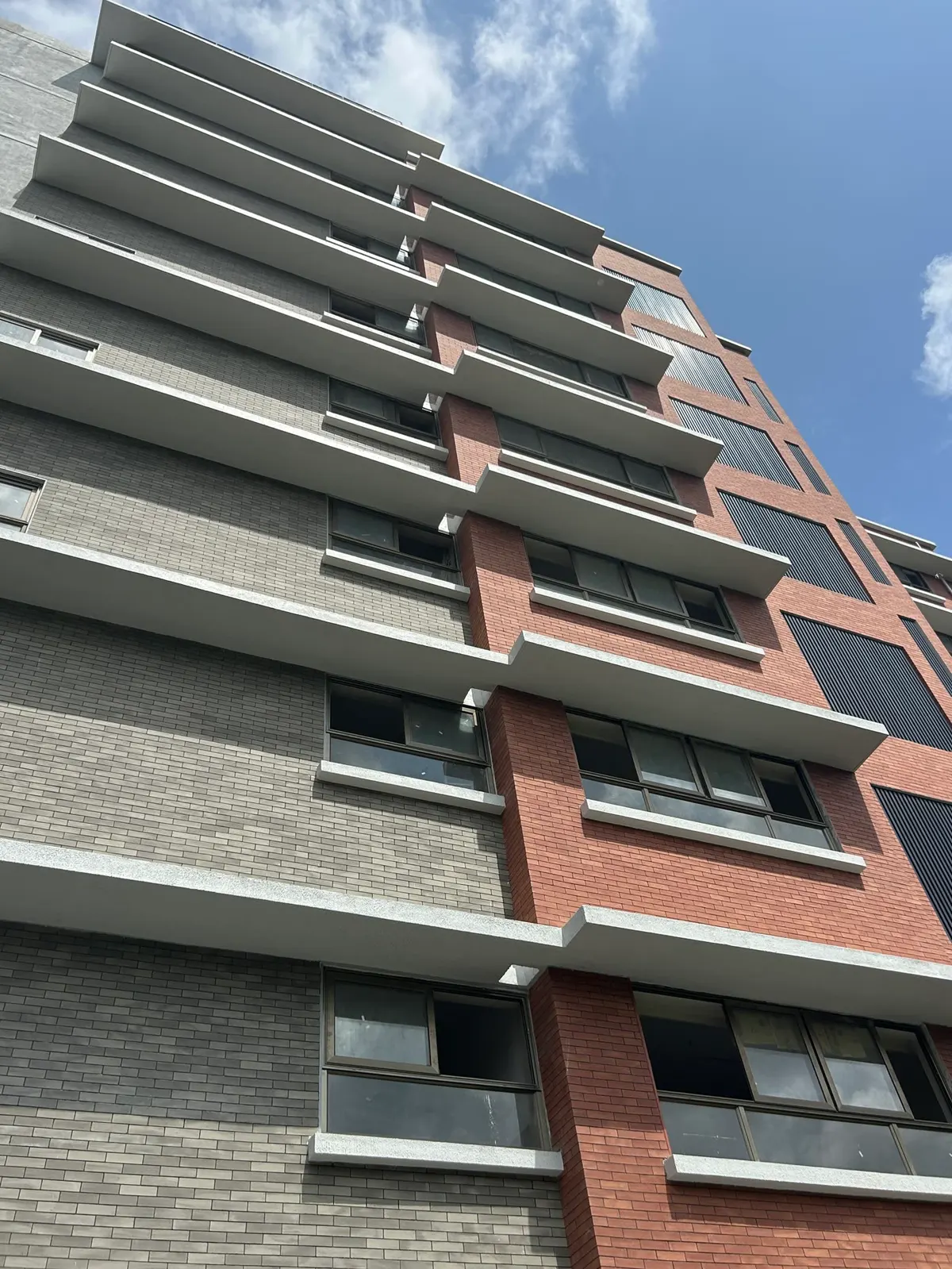 Fachada alta de ladrillo delgado con huecos y barandales